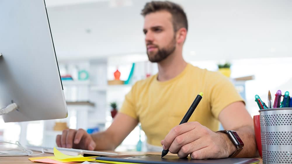 Hombre trabajando frente a un ordenador usando una tableta gráfica